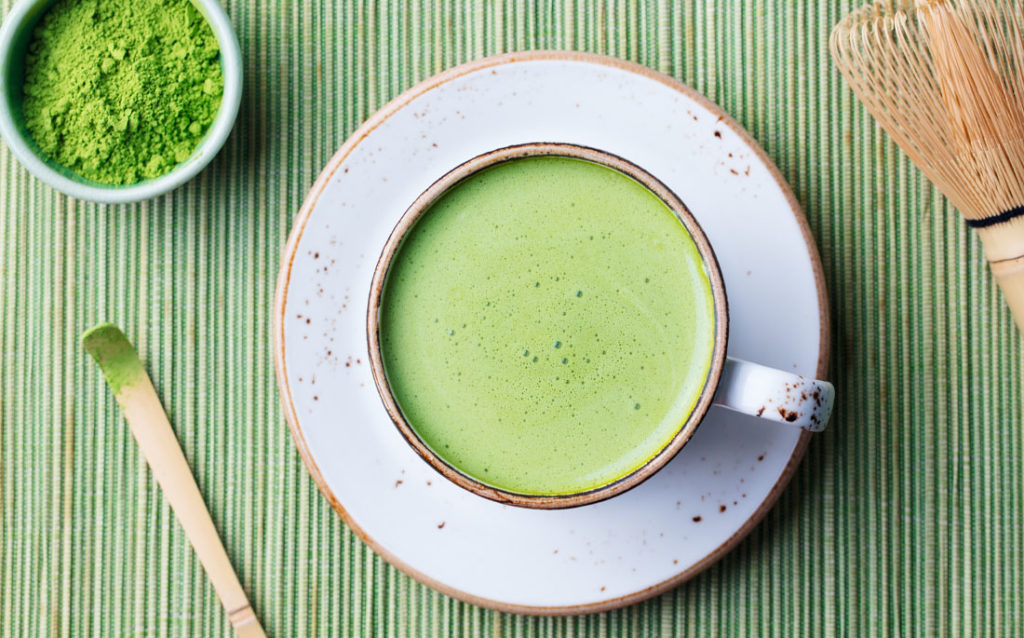 Photo showing a cup of the collagen-rich matcha latte, along with some green tea powder that makes it.
