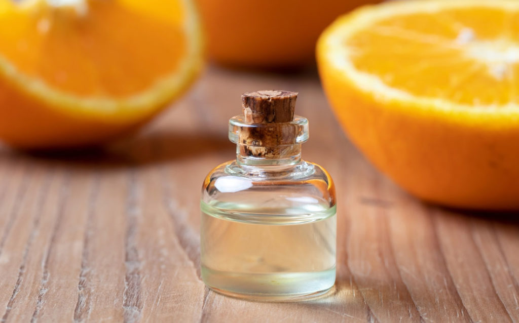 Photo showing bottle of orange-spiced cuticle oil and some oranges.